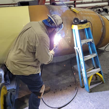 Mario in the fab shop welding a steel pipe fitting for a water transmission project.