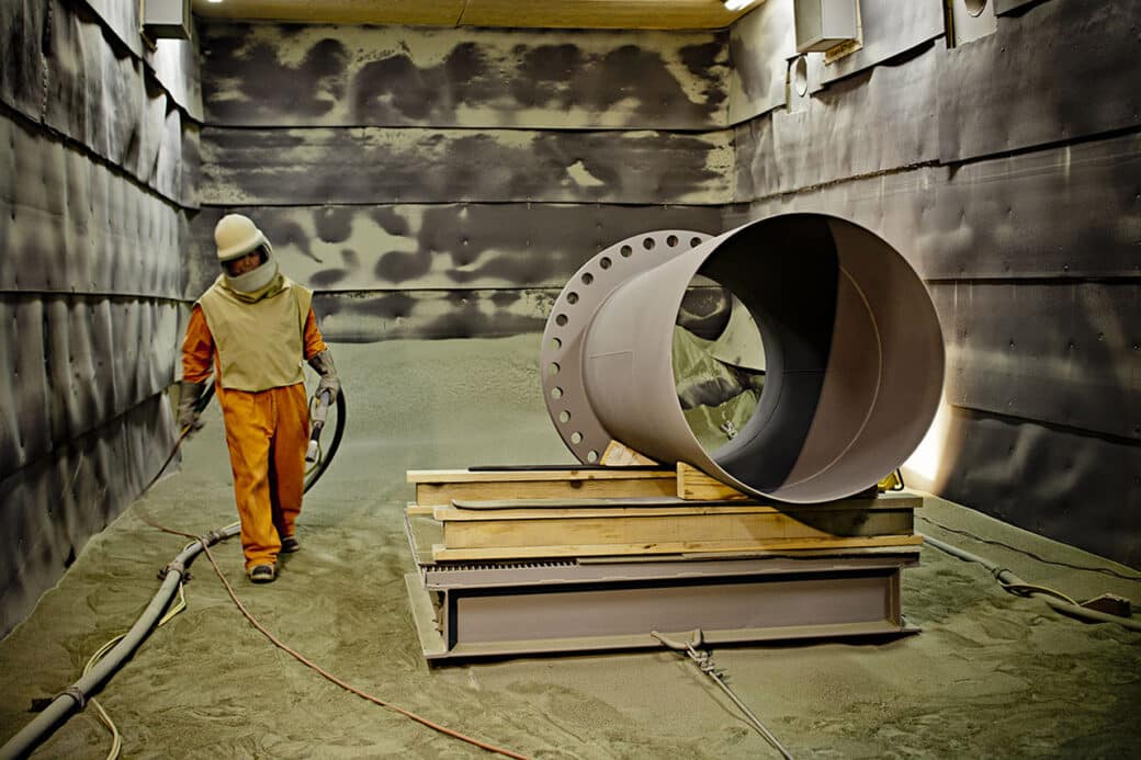 worker spraying pipe inside production facility