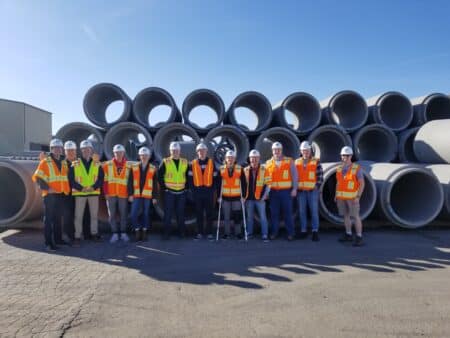 Workers pose in front of concrete pipes