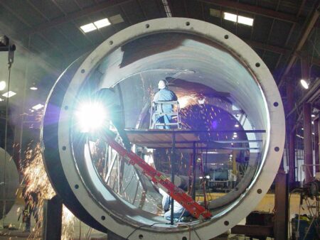 men inspecting and welding in large pipe
