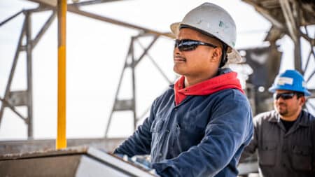 man operating machine in hard hat with glasses