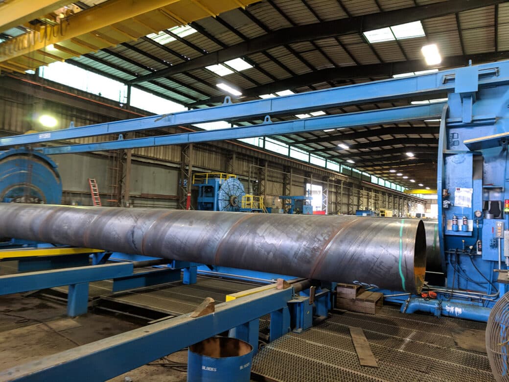 Engineered steel pipe being machine fabricated