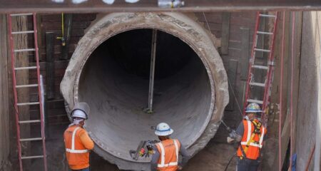 Construction workers excavating pipe