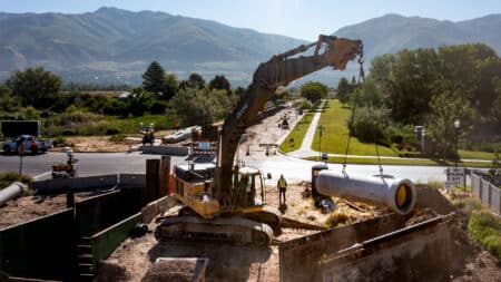 Crane lifting lined RCP into trench