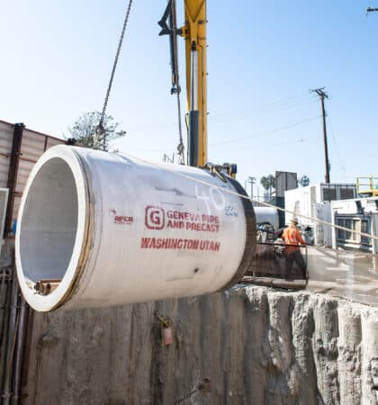 concrete jacking pipe being lifted by a crane into a shaft