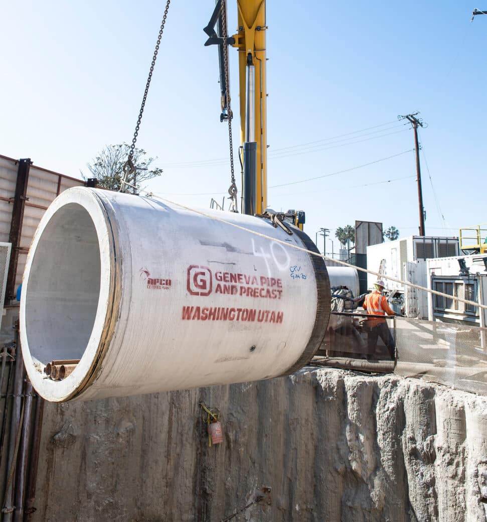 concrete jacking pipe being lifted by a crane into a shaft