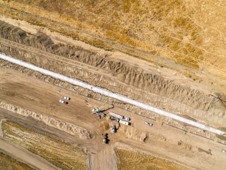 Aerial view of large diameter concrete pipe installed in a long line in a canal trench