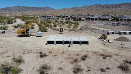 excavator lifting and moving box culvert into rows in desert lanscape