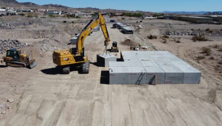 excavator lifting and moving box culvert into rows in desert lanscape