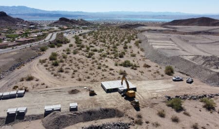 excavator lifting and moving box culvert into rows in desert lanscape