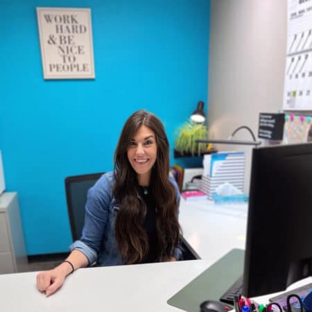 Woman smiling at desk in front of blue wall