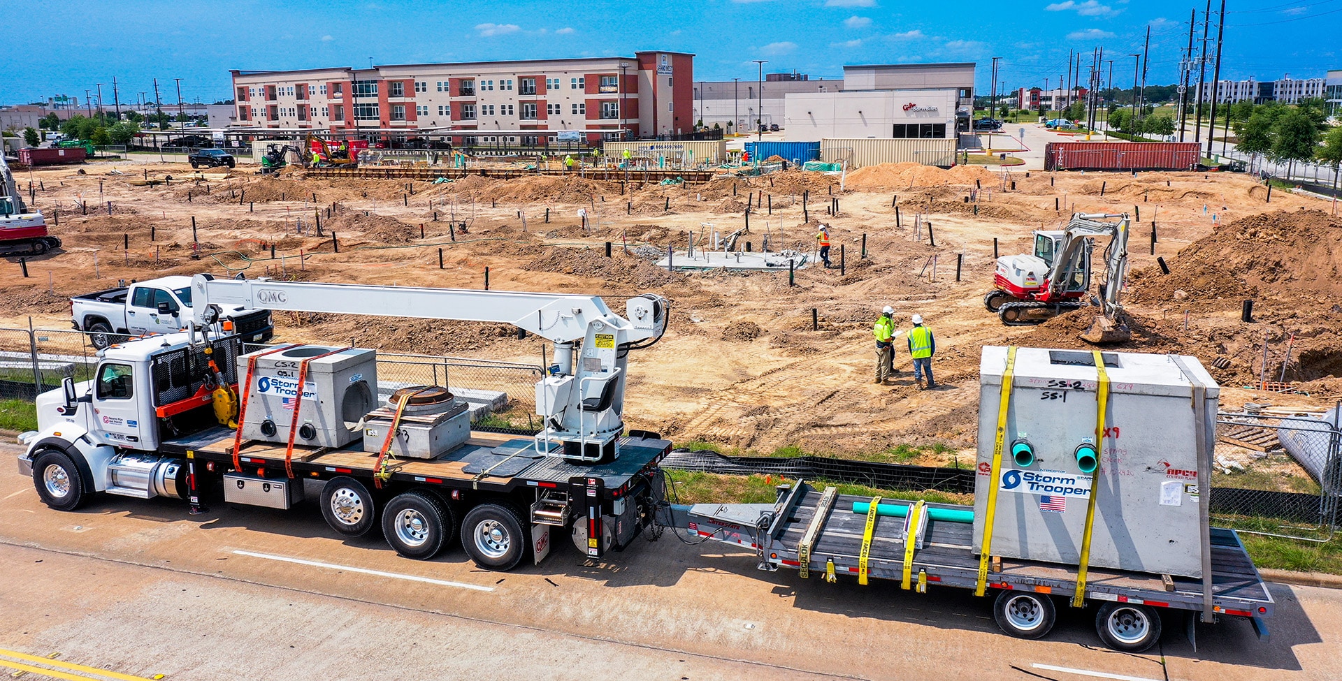 precast concrete vault on a truck bed in front of a construction site